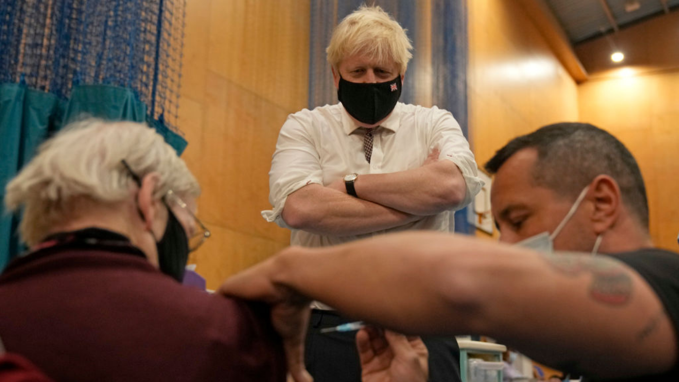 Boris Johnson watches a patient receive a booster jab