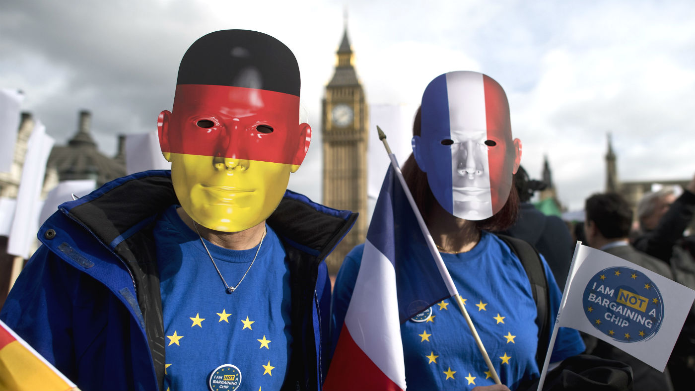 Pro-migrant protesters wearing German and French flag face masks outside Parliament in 2017
