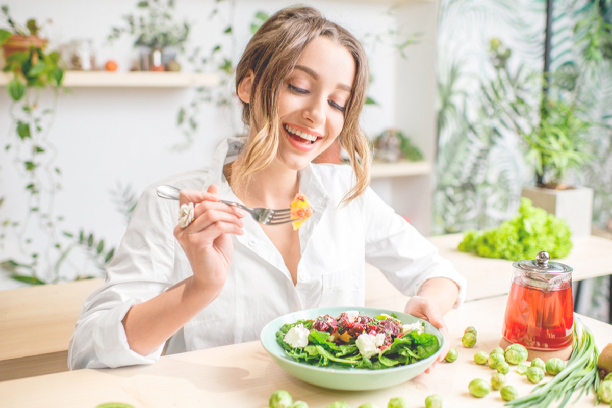 Woman sat at table eating salad with a fork