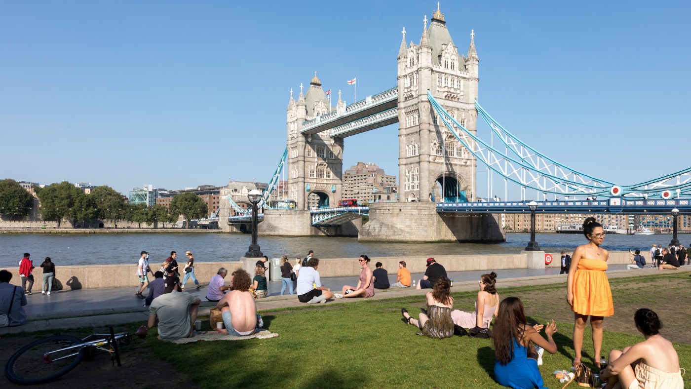 People sitting in the sun by Tower Bridge in London in September 2021
