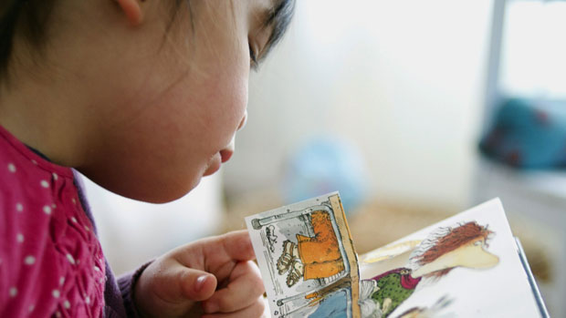 A young girl reads a children&#039;s book