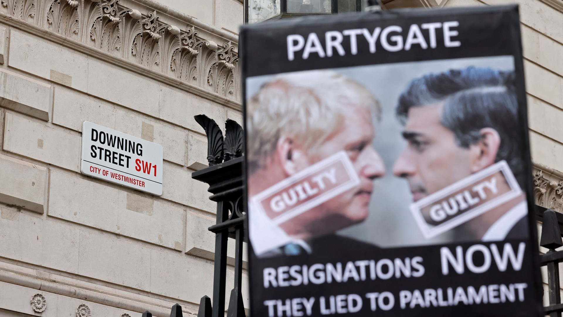 A demonstrator holds up a placard outside Downing Street calling for Boris Johnson and Rishi Sunak to resign 