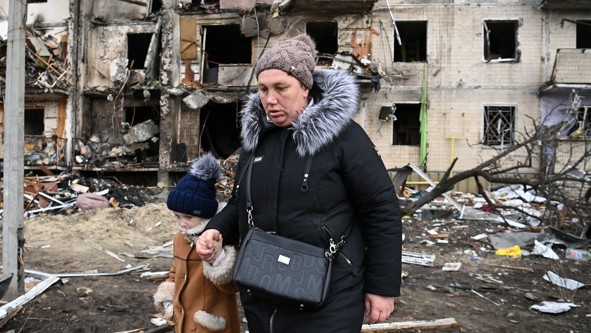 A woman and child outside a damaged residential building in Kyiv