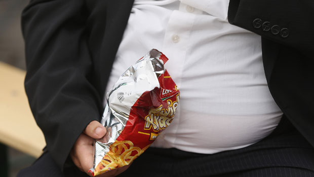 An overweight man eating junk food