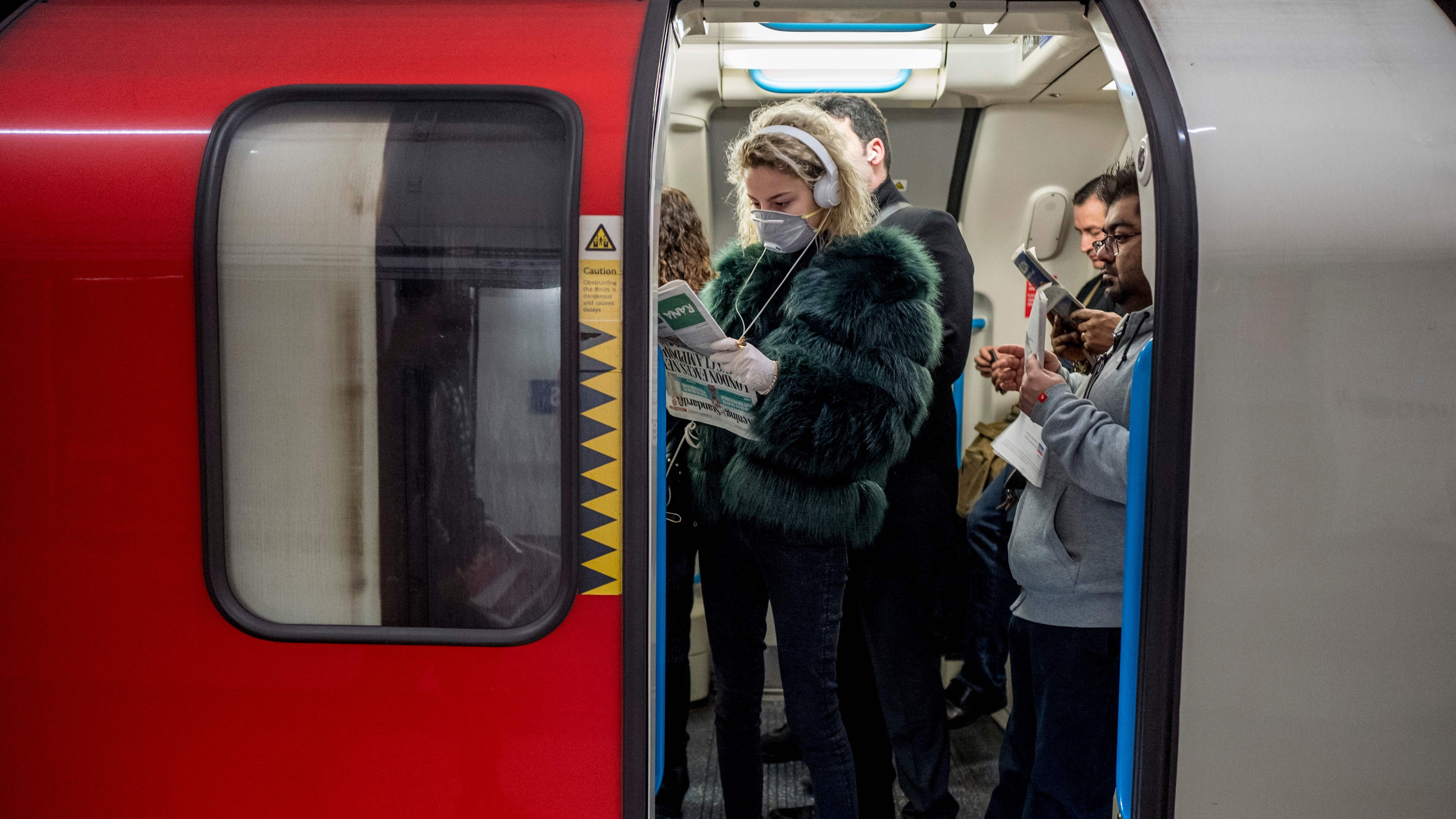 A commuter wears a mask while travelling on the London Underground