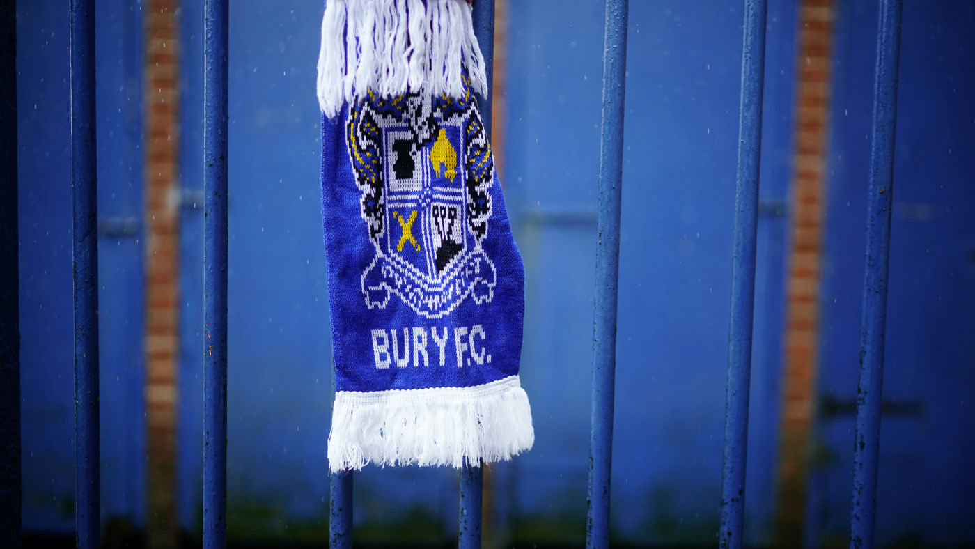 Bury FC scarves hang on a fence outside the EFL League One club’s Gigg Lane stadium