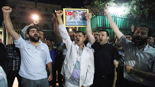 Supporters of Egyptian President Morsi shout slogans during a support rally in Ankara ON July 3, 2013. In Cairo, tens of thousands cheered, ignited firecrackers and honked horns as soon as th