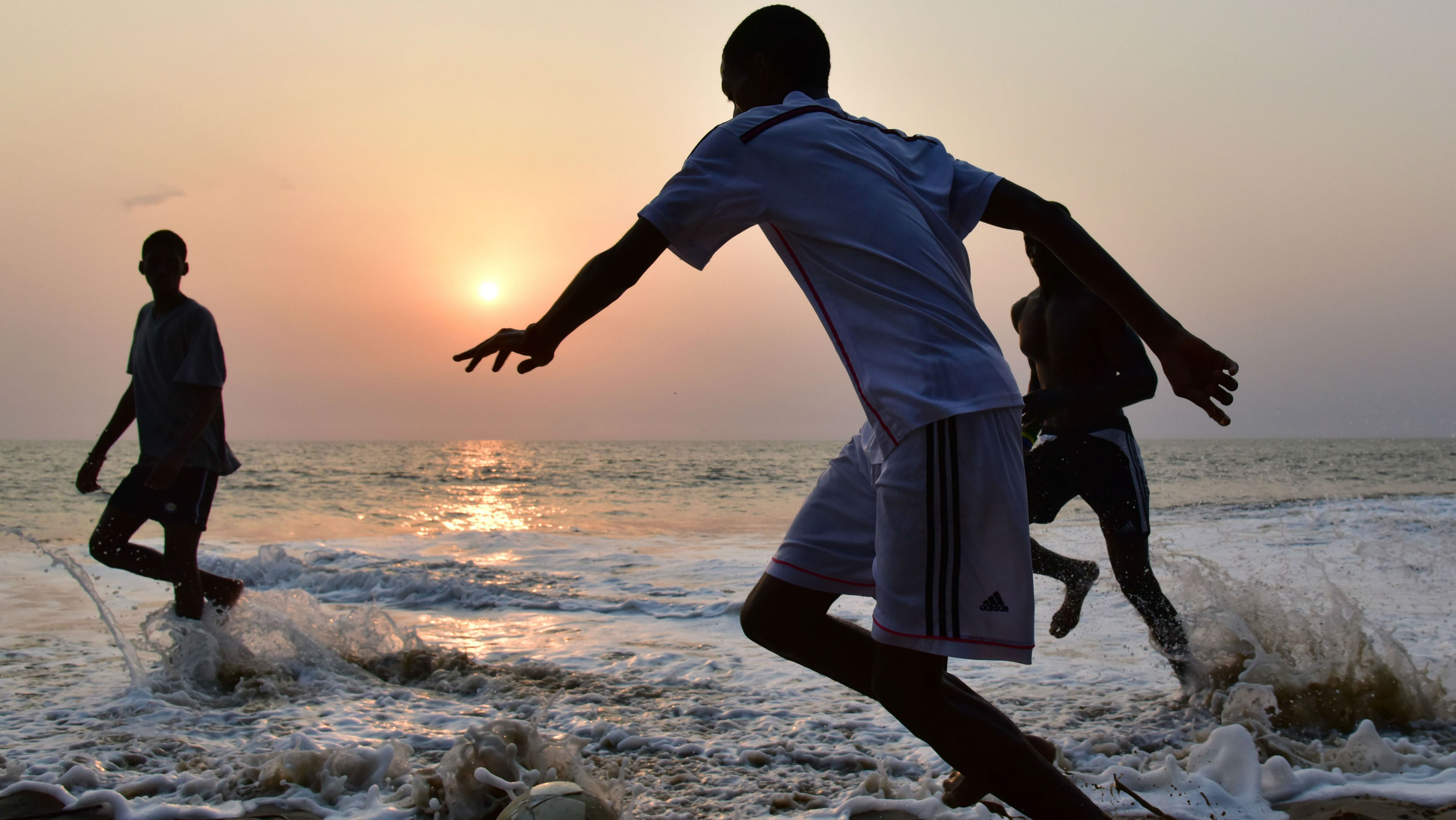 Boys play football on a beach in Gabon 