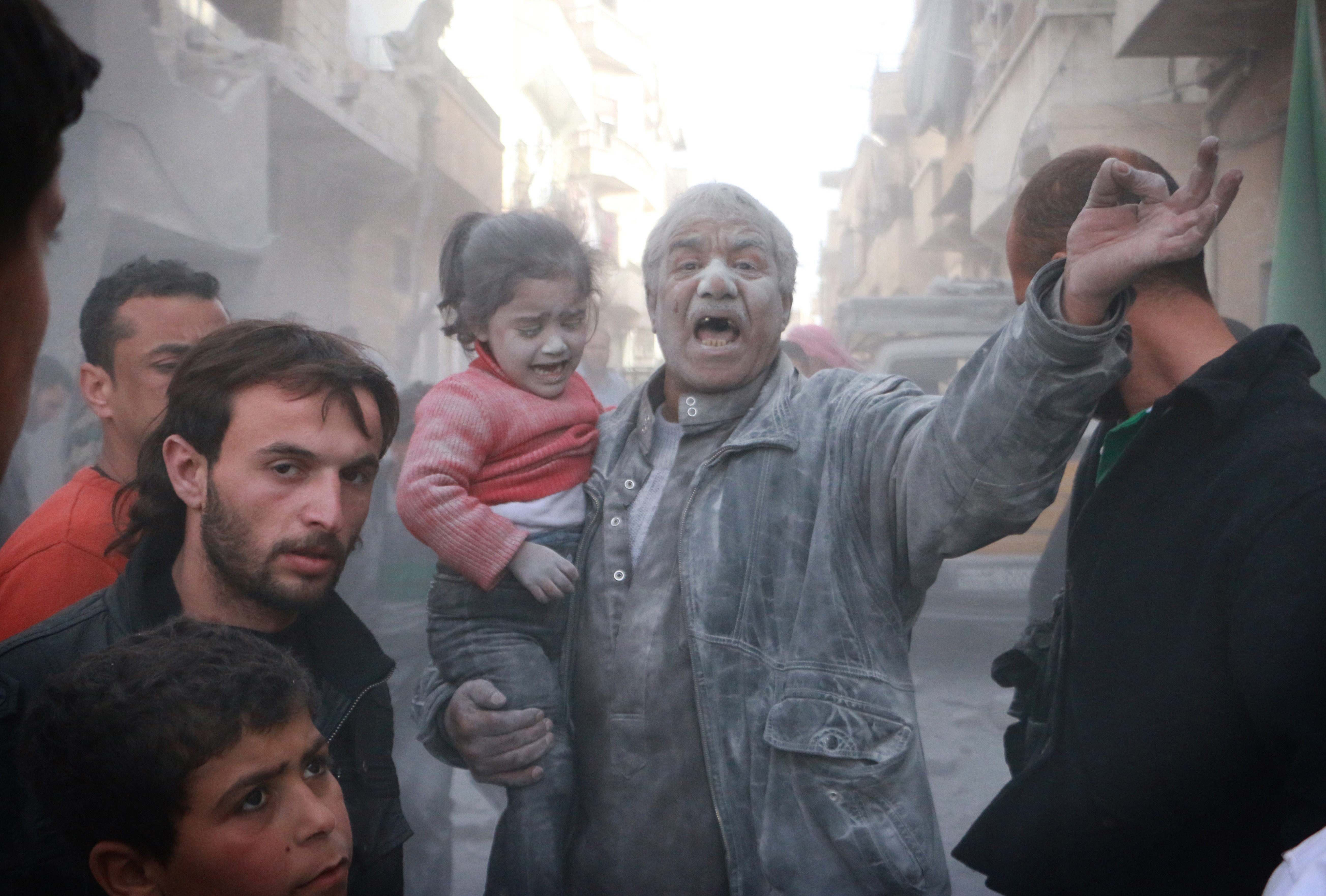 A Syrian man holds a crying girl as he gestures following an air strike by government forces on the Sahour neighbourhood of the northern Syrian city of Aleppo on March 6, 2014. AFP PHOTO / FA