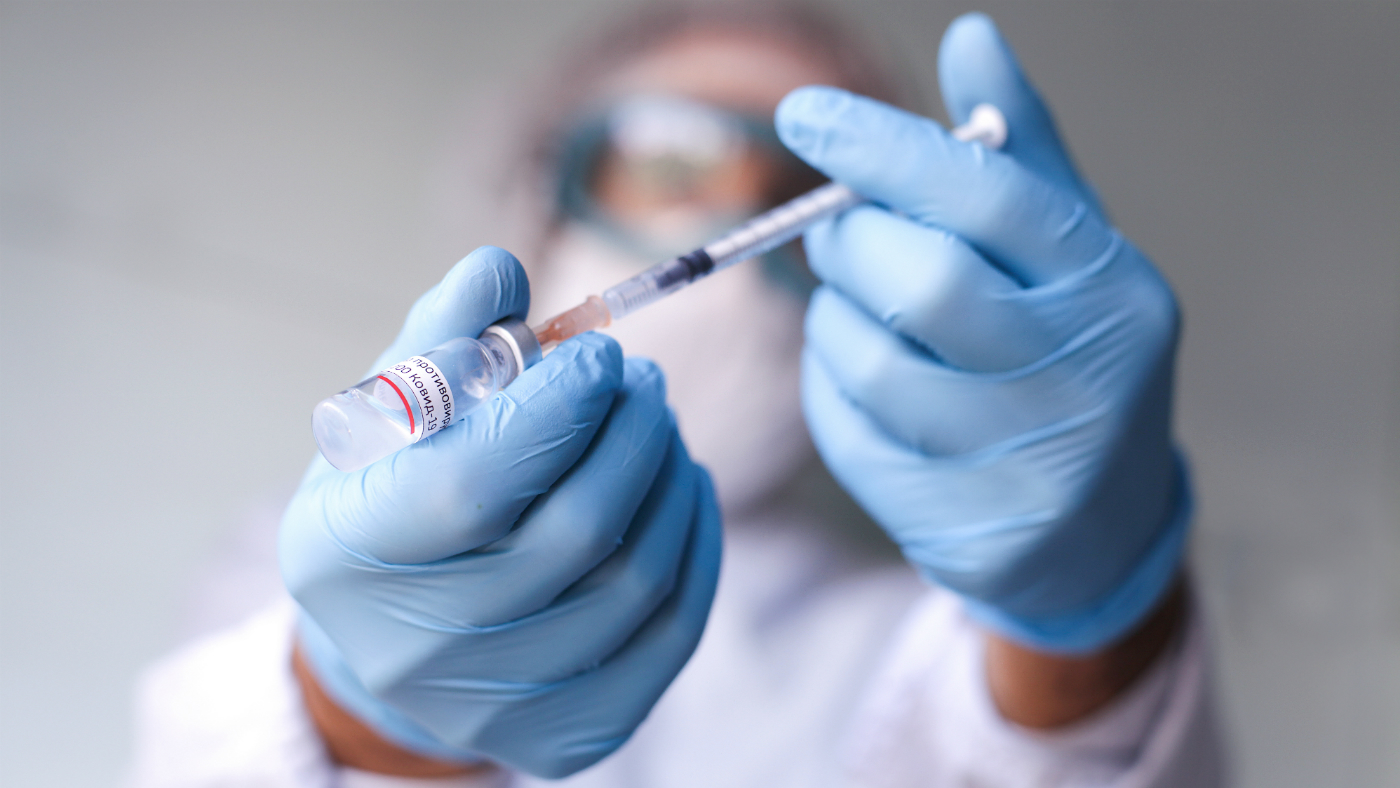 A doctor wearing sterile gloves prepares a vaccination injection.