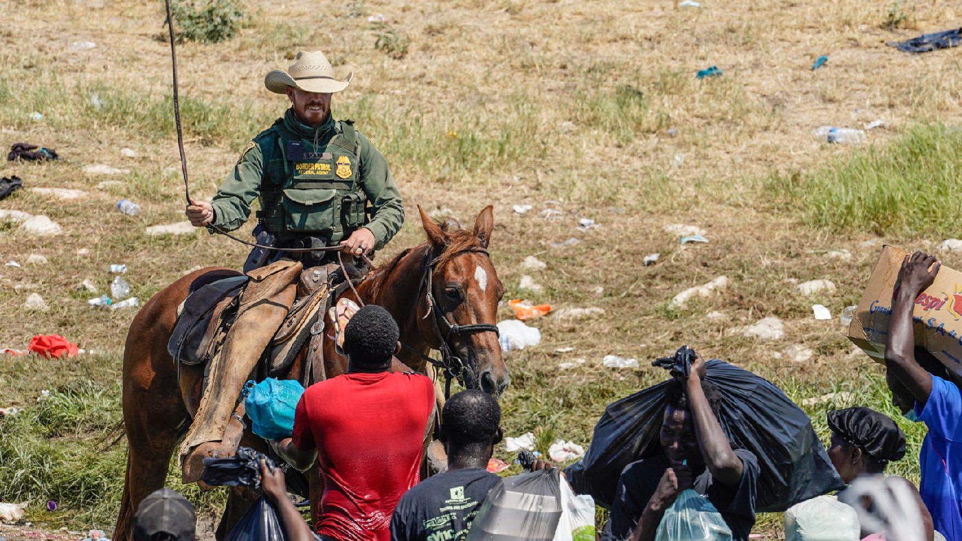 A United States Border Patrol agent on horseback tries to stop Haitian migrants from entering an encampment