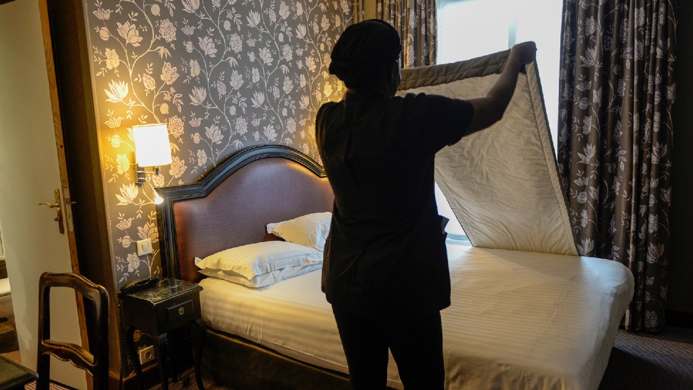 Hotel staff member changing bed sheets 