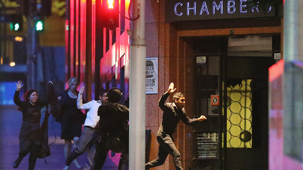SYDNEY, AUSTRALIA - DECEMBER 15:People run with there hands up from the Lindt Cafe, Martin Place during a hostage standoff on December 15, 2014 in Sydney, Australia.Police stormed the Sydney 