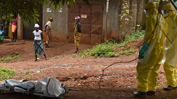 Health workers from in Sierra Leone&#039;s stand near a corpse 