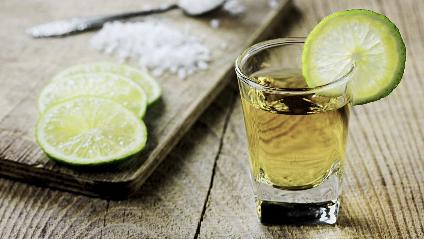 Tequila shot with lime and salt on vintage wooden background