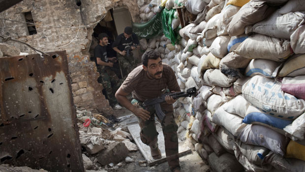 Syrian rebels take cover behind a barricade in Aleppo