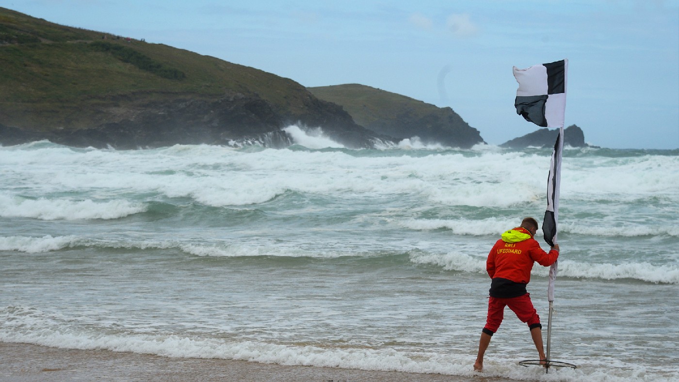 A lifeguard puts out a chequered flag