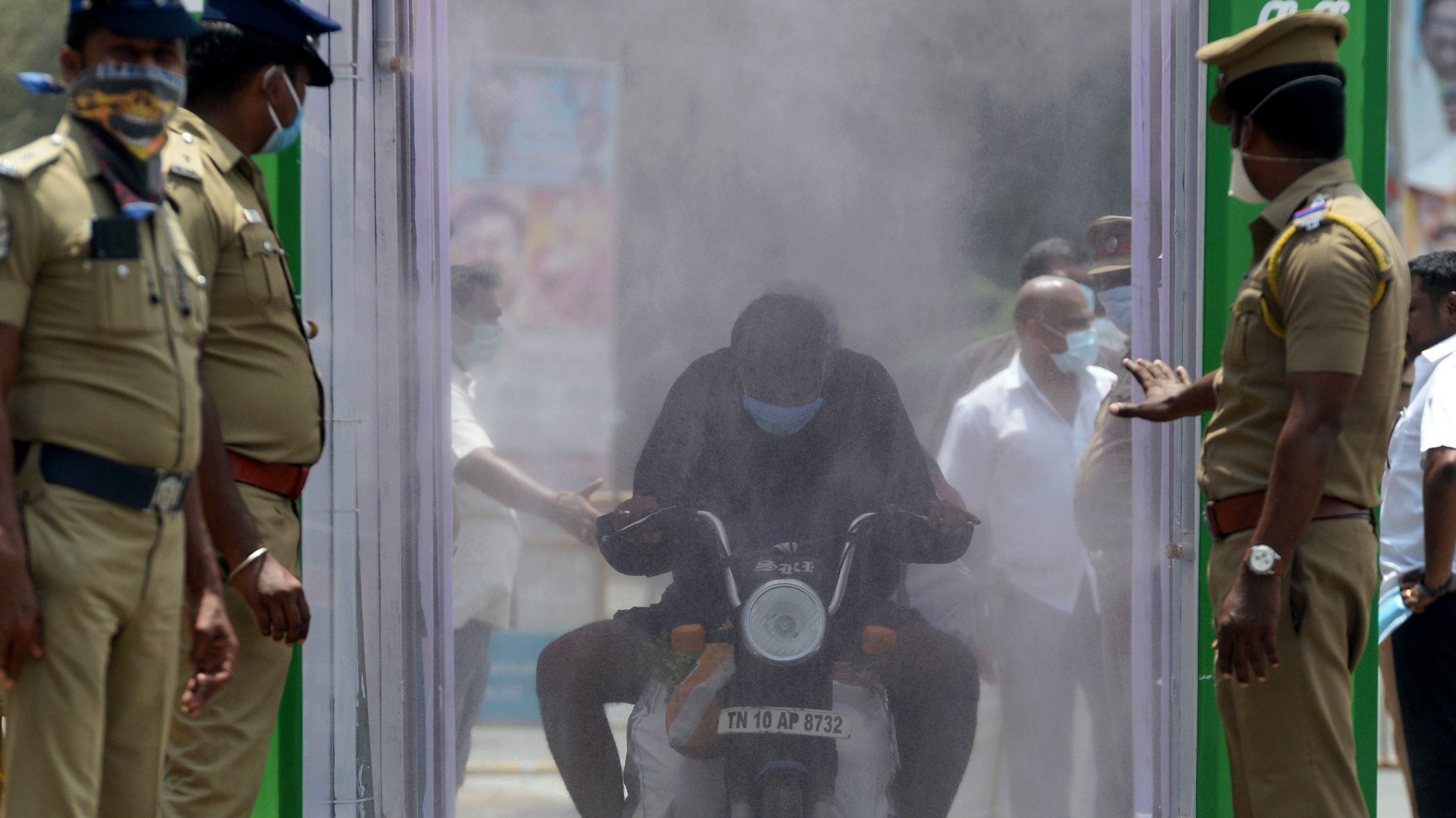 A motorcyclist rides through a disinfection tunnel in Chennai