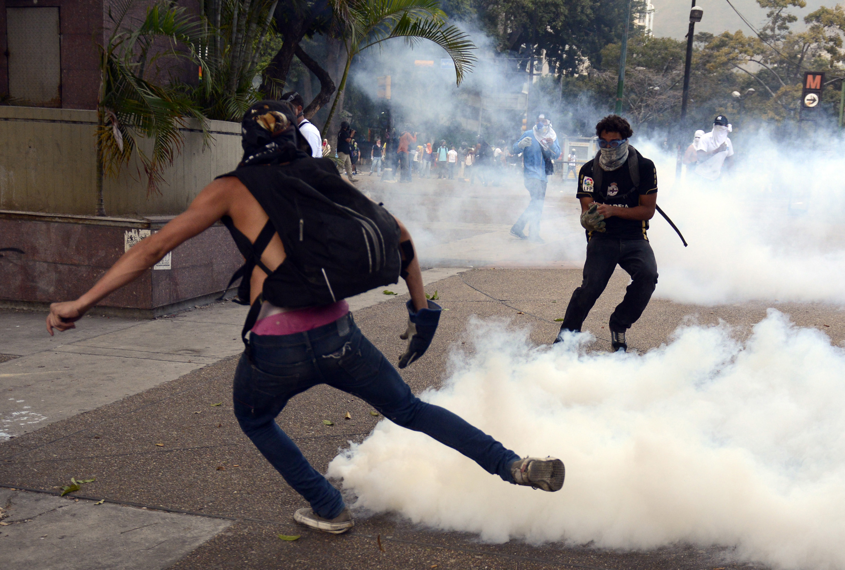 Opposition activists returns tear gas to riot police during a protest against the government of Venezuelan President Nicolas Maduro in Caracas on March 6, 2014. A member of the National Guard