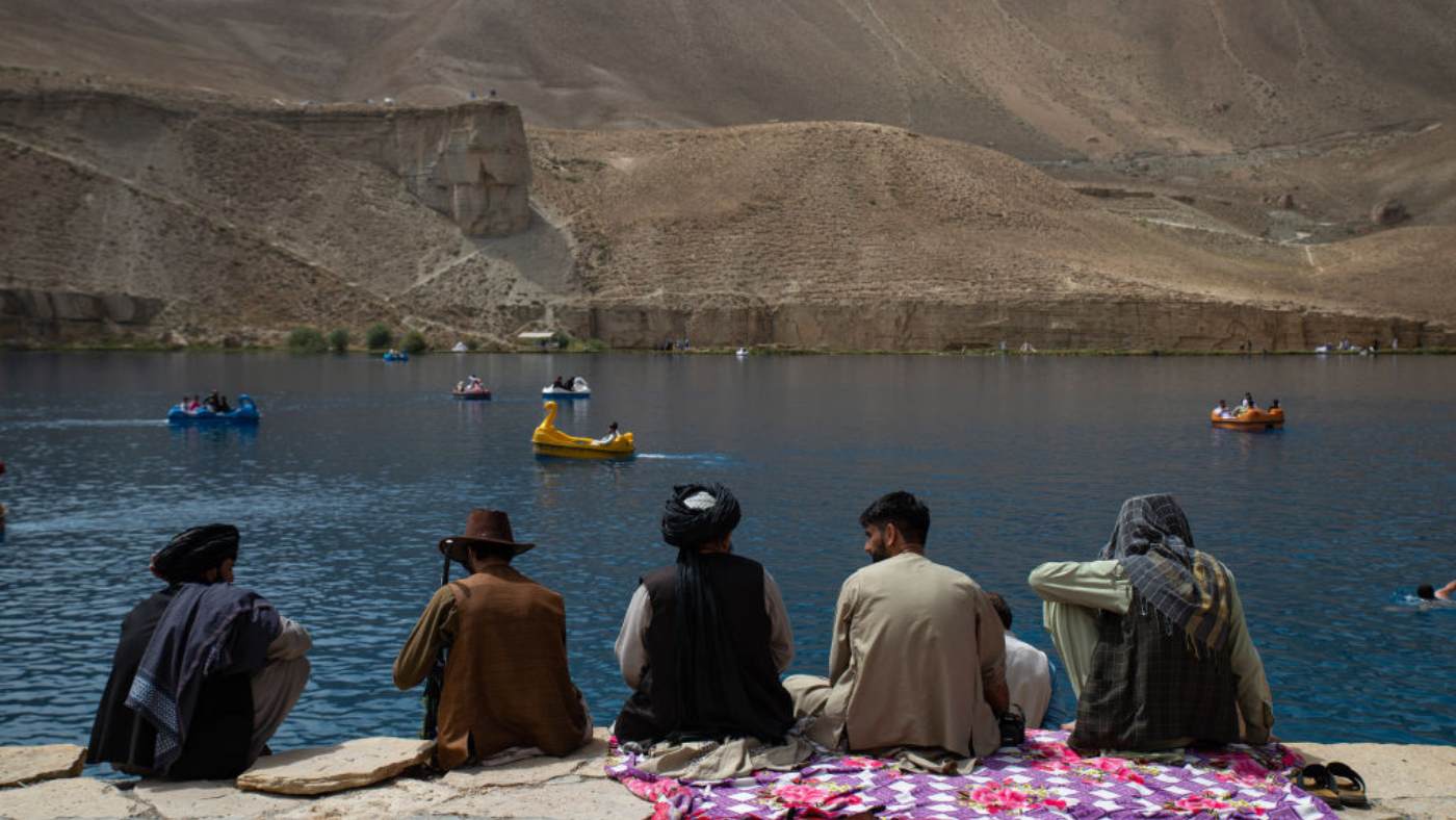 Members of the Taliban watch as some people ride pedalos on a lake