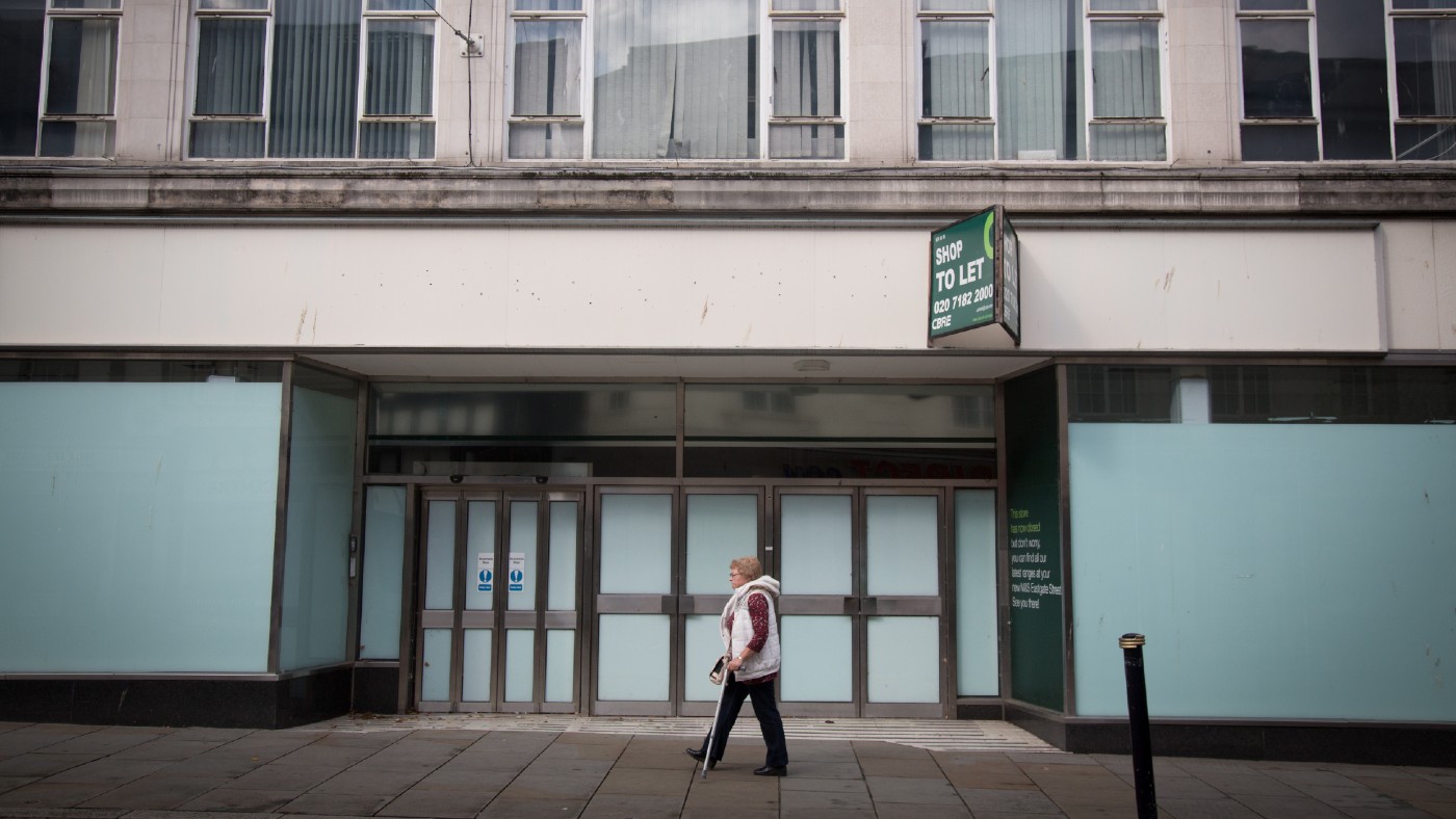 A woman passes an empty shop on a high street in Gloucester, England 
