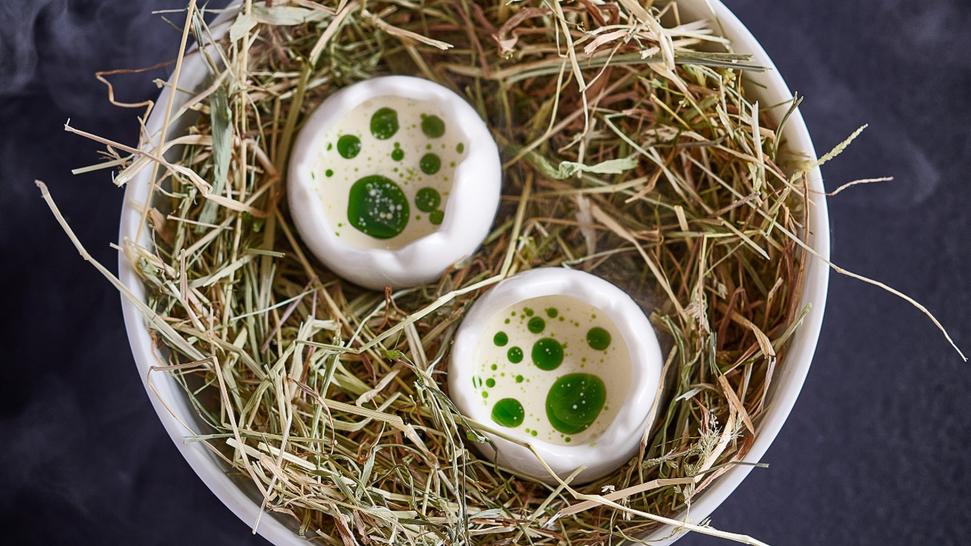 Egg, bacon and maitake mushrooms served in egg cups on a nest of hay