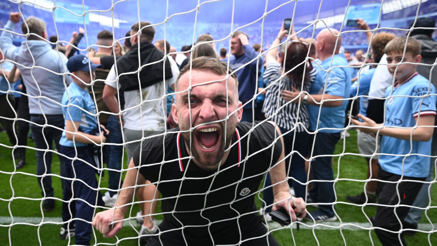A Manchester City fan celebrates on the pitch after his side won the Premier League title