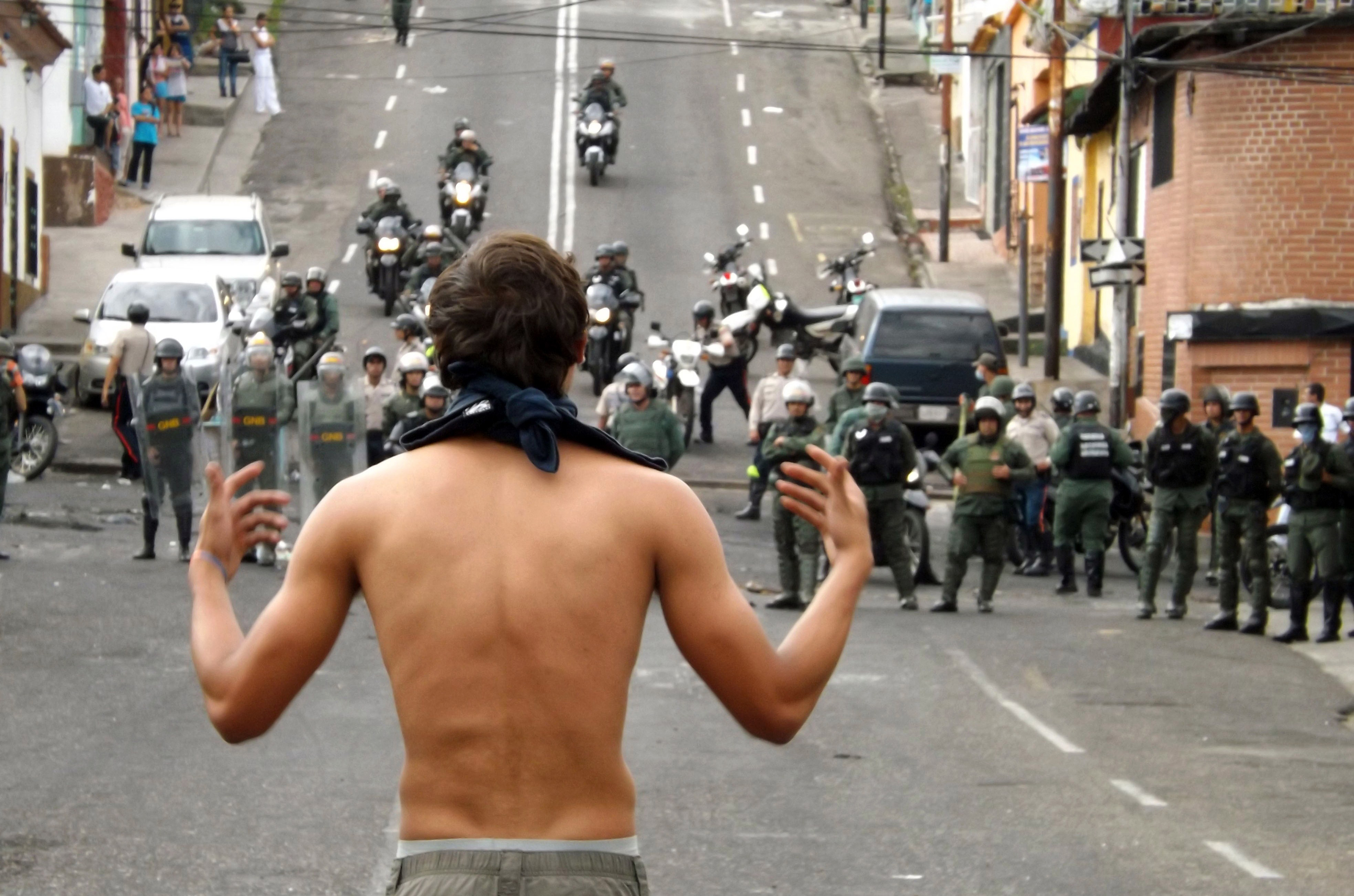 An activists faces National Guard troopers during a protest in San Cristobal, capital of the western border state of Tachira, Venezuela, on February 27, 2014. Dueling demos of pro- and anti-g