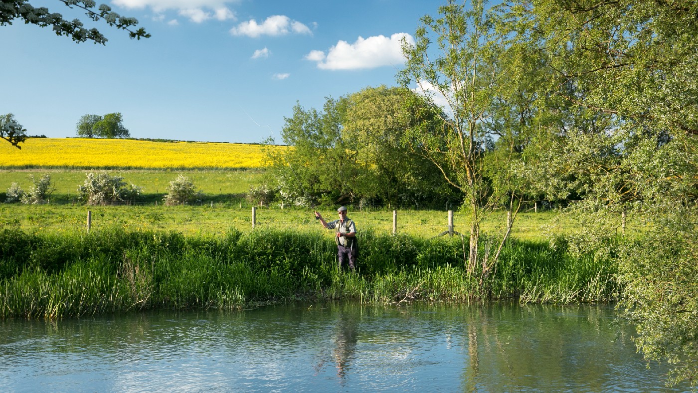 A fisherman fly fishing in the River Windrush