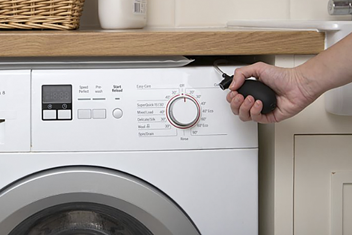 A hand holding a bulb to inflate a Steady Spin bag on top of a washing machine