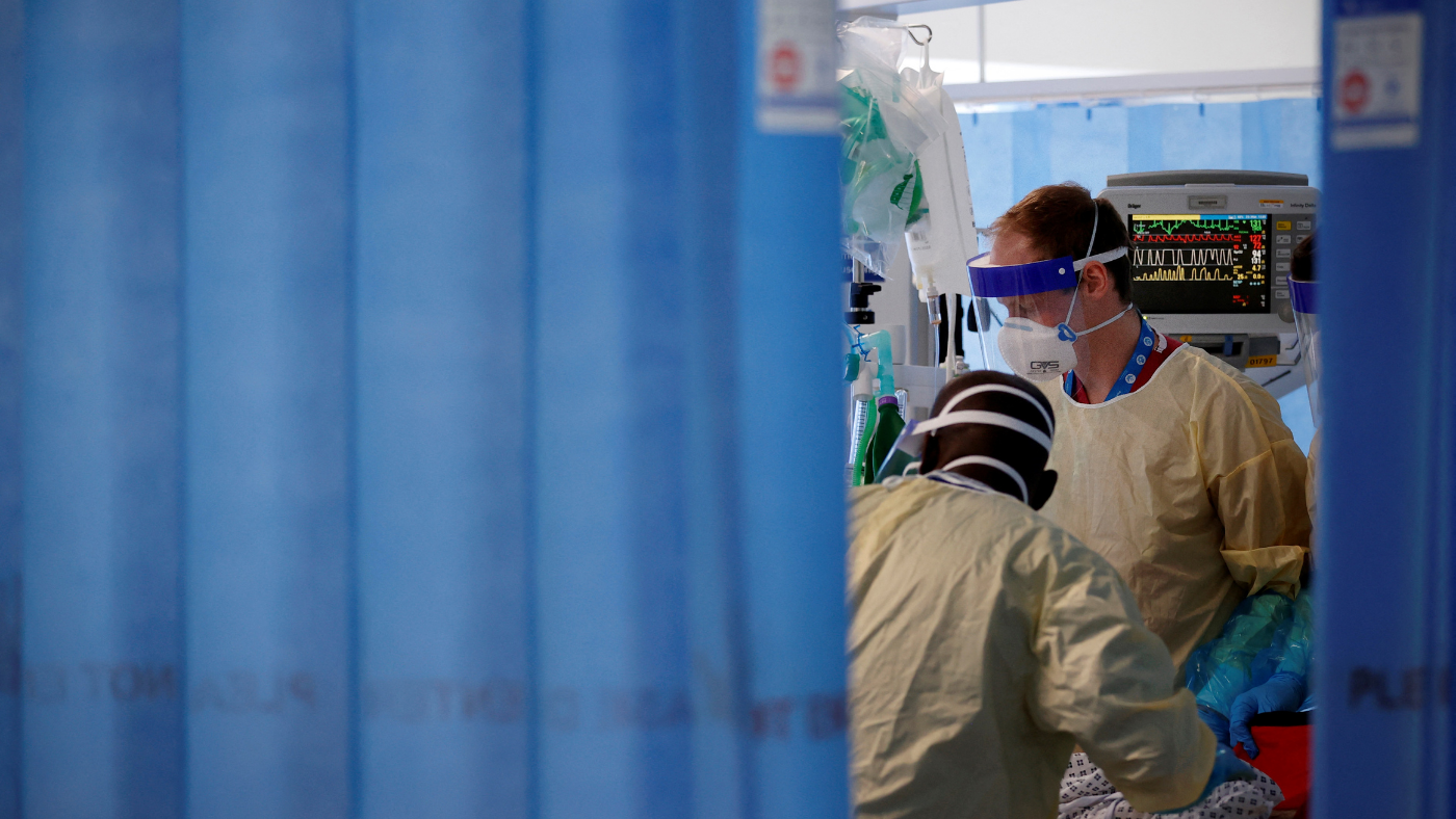 Doctors treat patient in hospital wearing PPE 