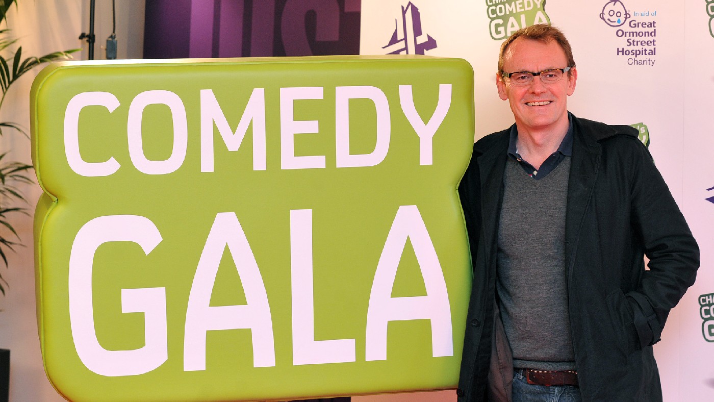 Sean Lock posing by a sign reading Comedy Gala