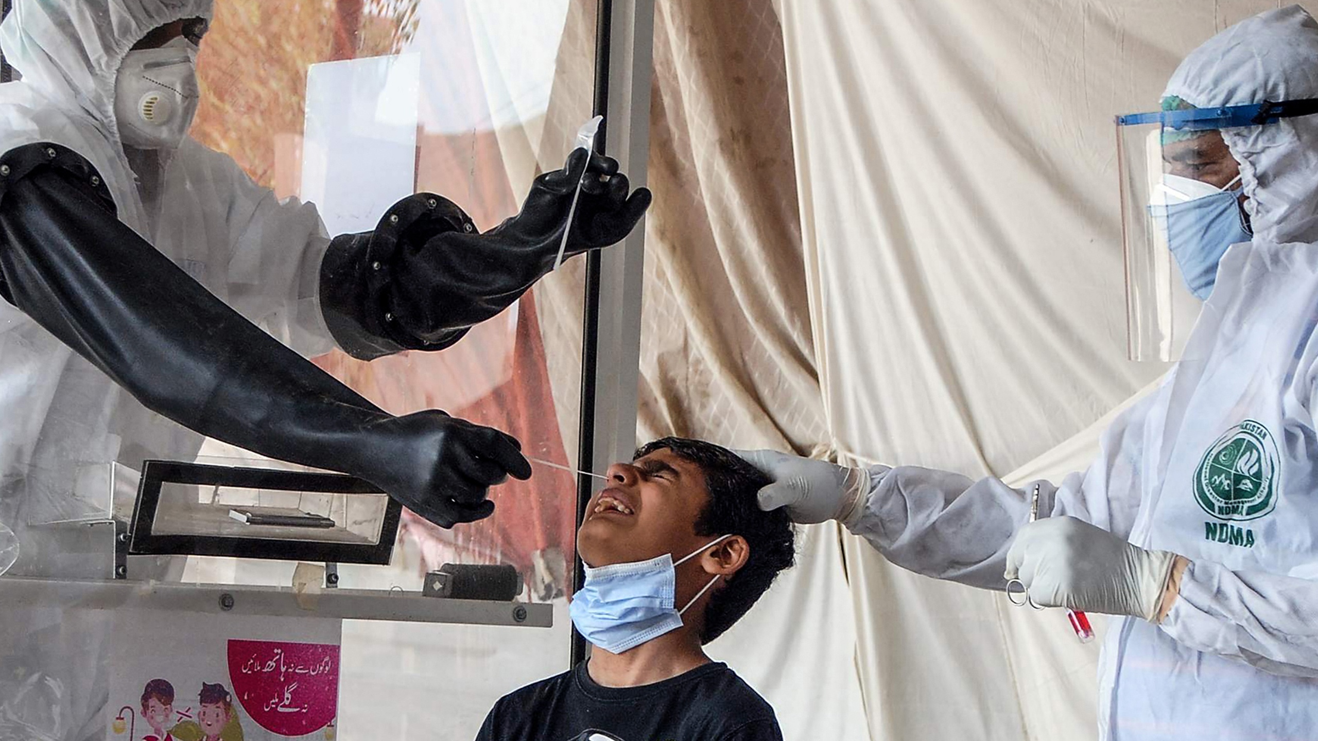 Health workers take a nasal swab from a boy in Karachi