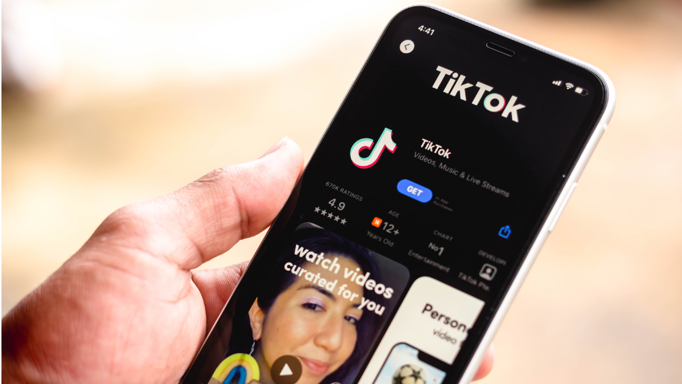 Hand holding smartphone showing TikTok