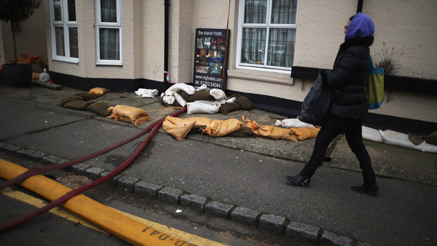 DATCHET, UNITED KINGDOM - FEBRUARY 17:A woman navigates past sandbags on February 17, 2014 in Chertsey, United Kingdom. The Environment Agency continues to issue severe flood warnings for a n