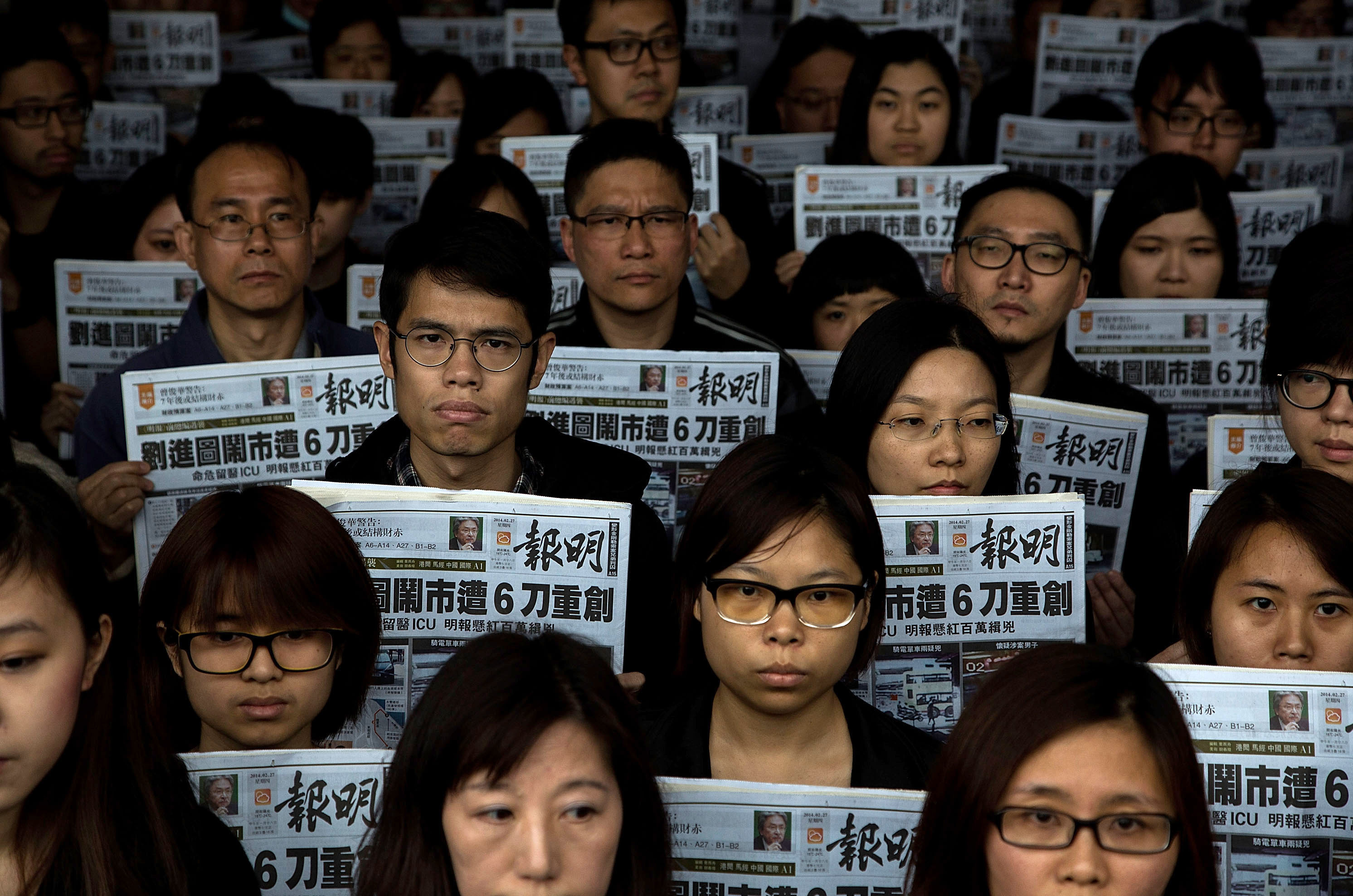 HONG KONG - FEBRUARY 27:Staff members of Ming Pao hold its newspaper printed on February 27, 2014 in which former chief editor of Ming Pao kevin Lau Chun-to was stabbed as front page story du