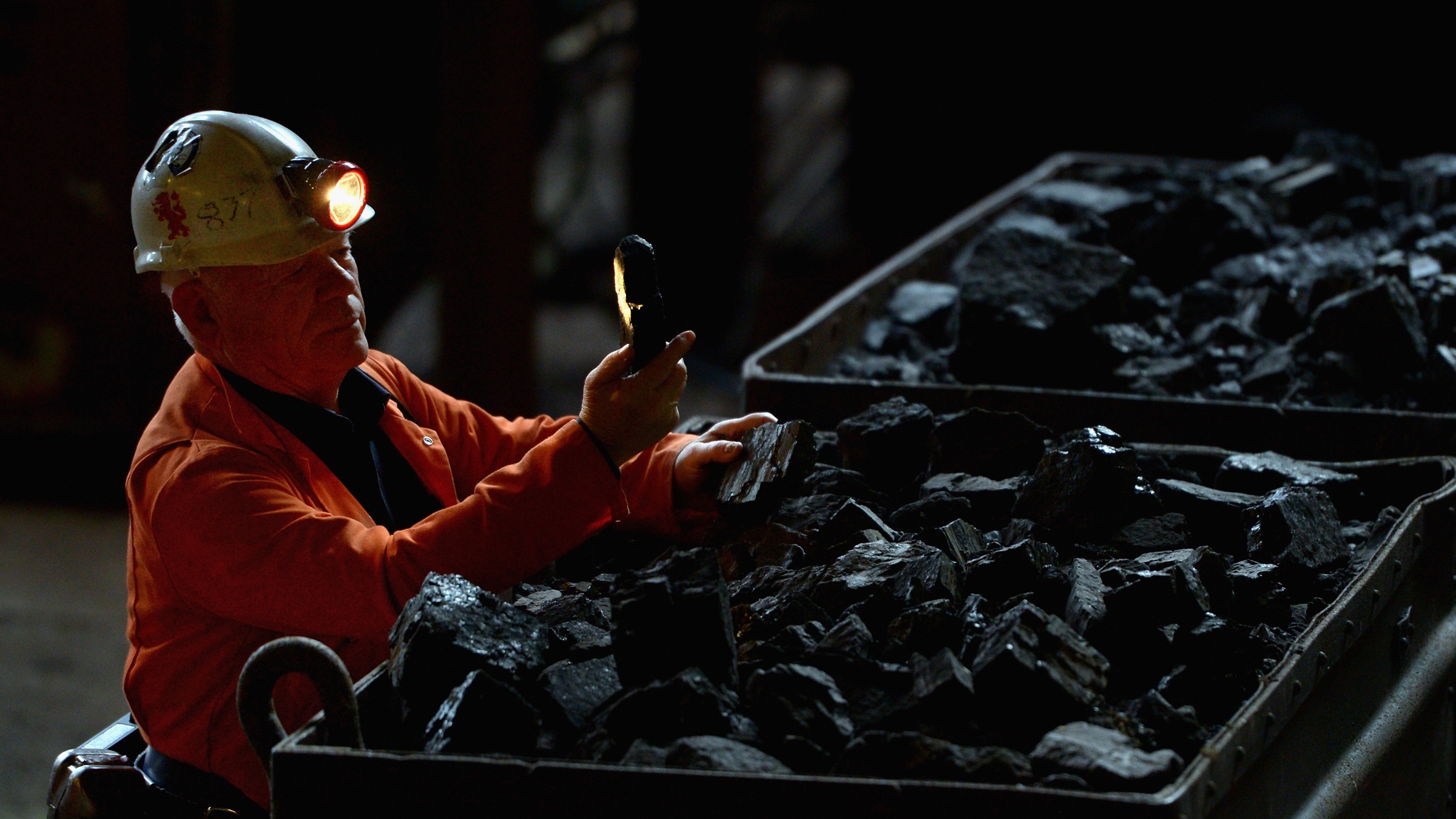 A coal miner inspects a piece of coal.