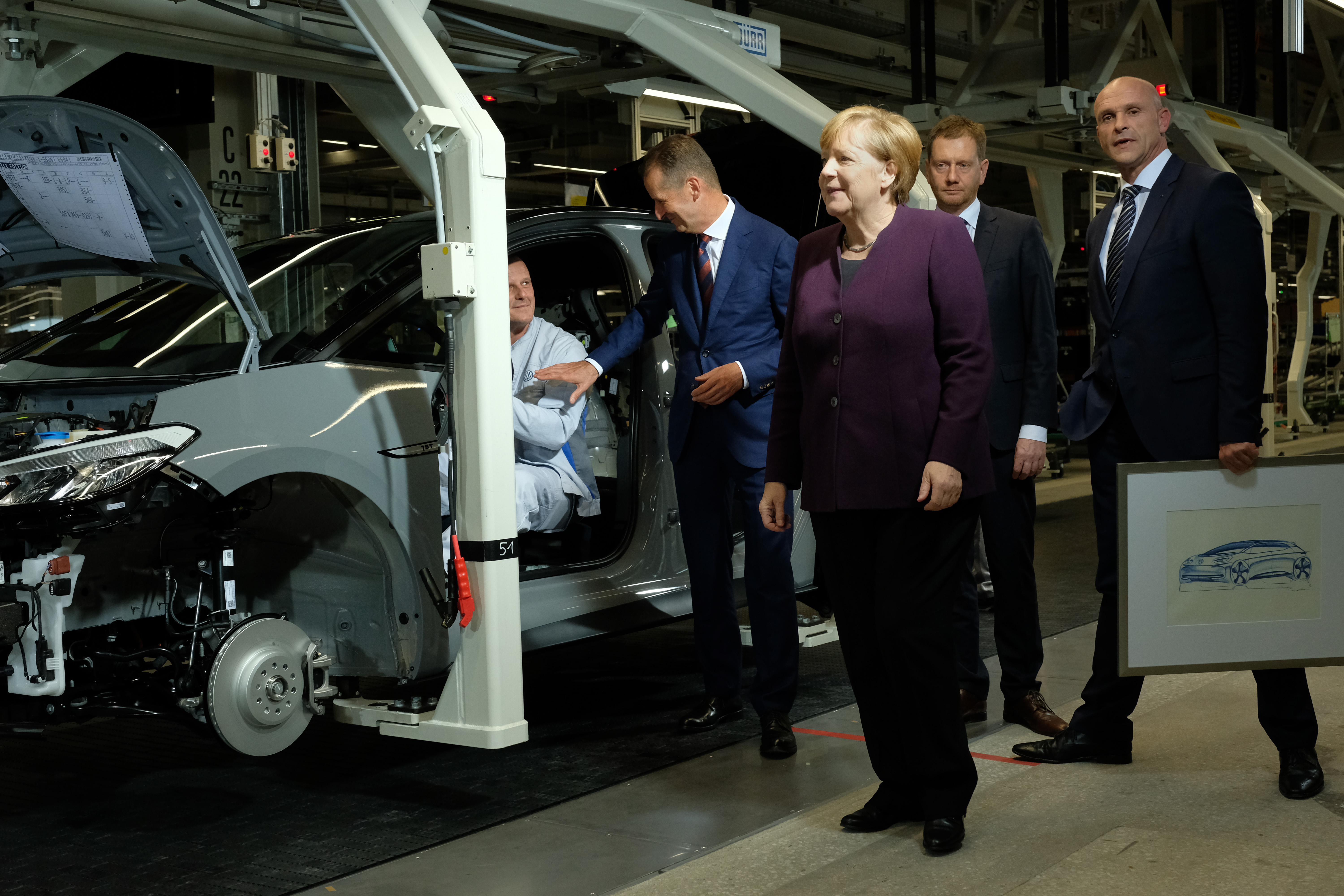 ZWICKAU, GERMANY - NOVEMBER 04: German Chancellor Angela Merkel (C) visits the assembly line of the new Volkswagen ID.3 electric car accompanied by Herbert Diess (L of Merkel), head of Volksw