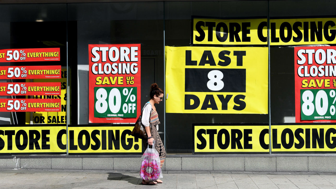 A pedestrian walks past a shop with a closing down sale promotion in Liverpool