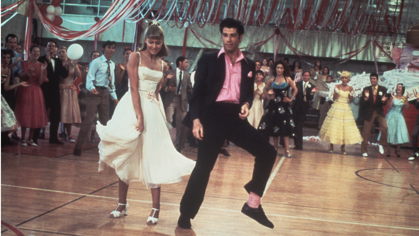 Newton-John and Travolta dance in a crowded high school gym