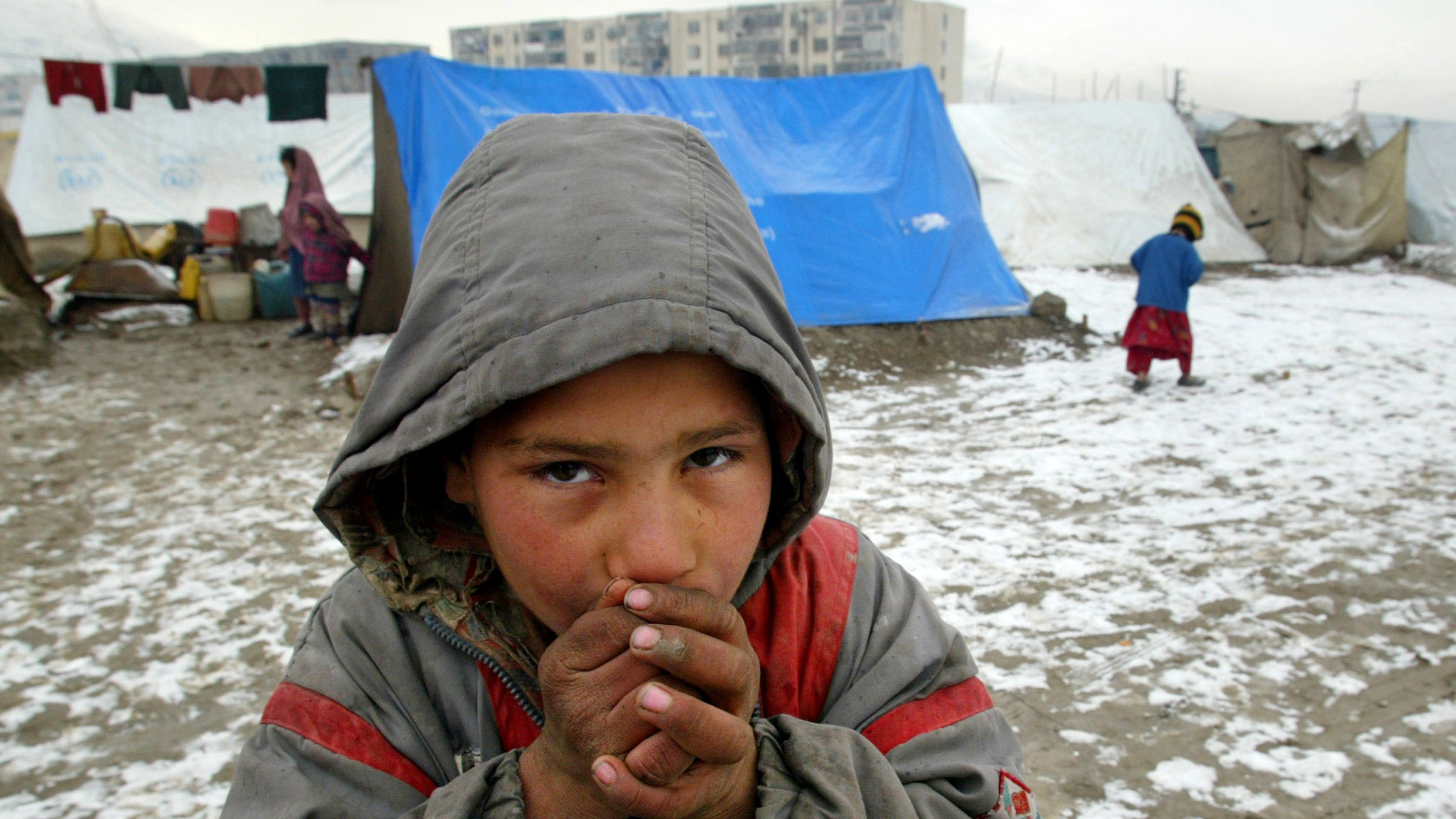 A child attempts to keep warm following snowfall outside Herat, Afghanistan