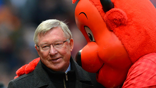 Manchester United manager Alex Ferguson (L) is hugged by mascot Fred The Red as he makes his way to the bench before the English Premier League football match between Manchester United and Re