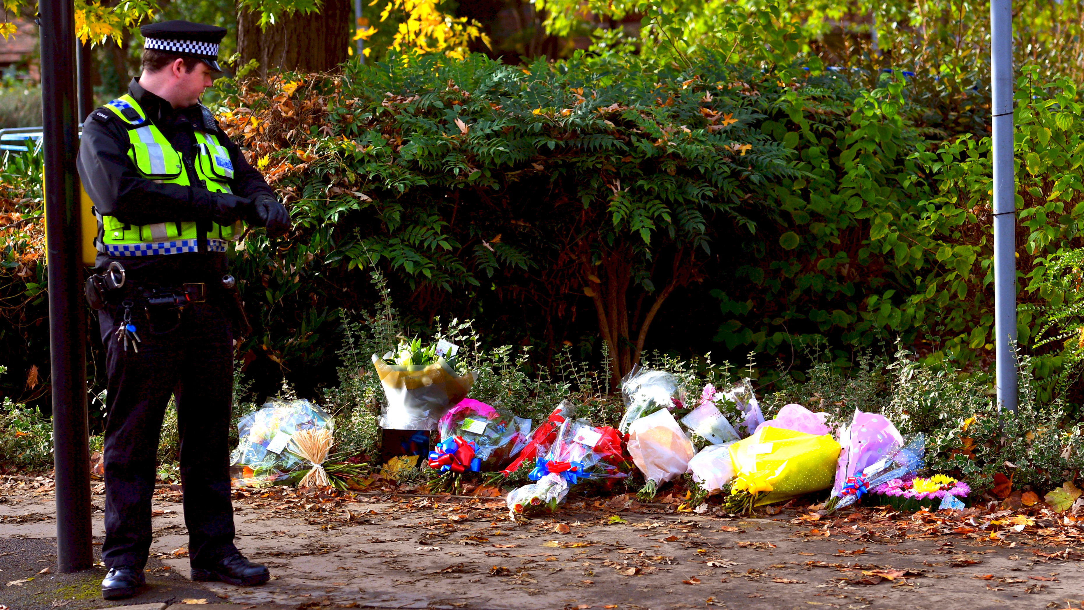 A police officer looks at flowers left near the scene of a fatal tram crash in Croydon, south London