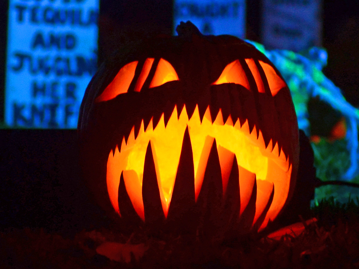 A carved and lit pumpkin is placed among what appears to be tombstones in a neighborhood decorated for Halloween in Sierra Madre, California, on October 31, 2013 as people young and old celeb