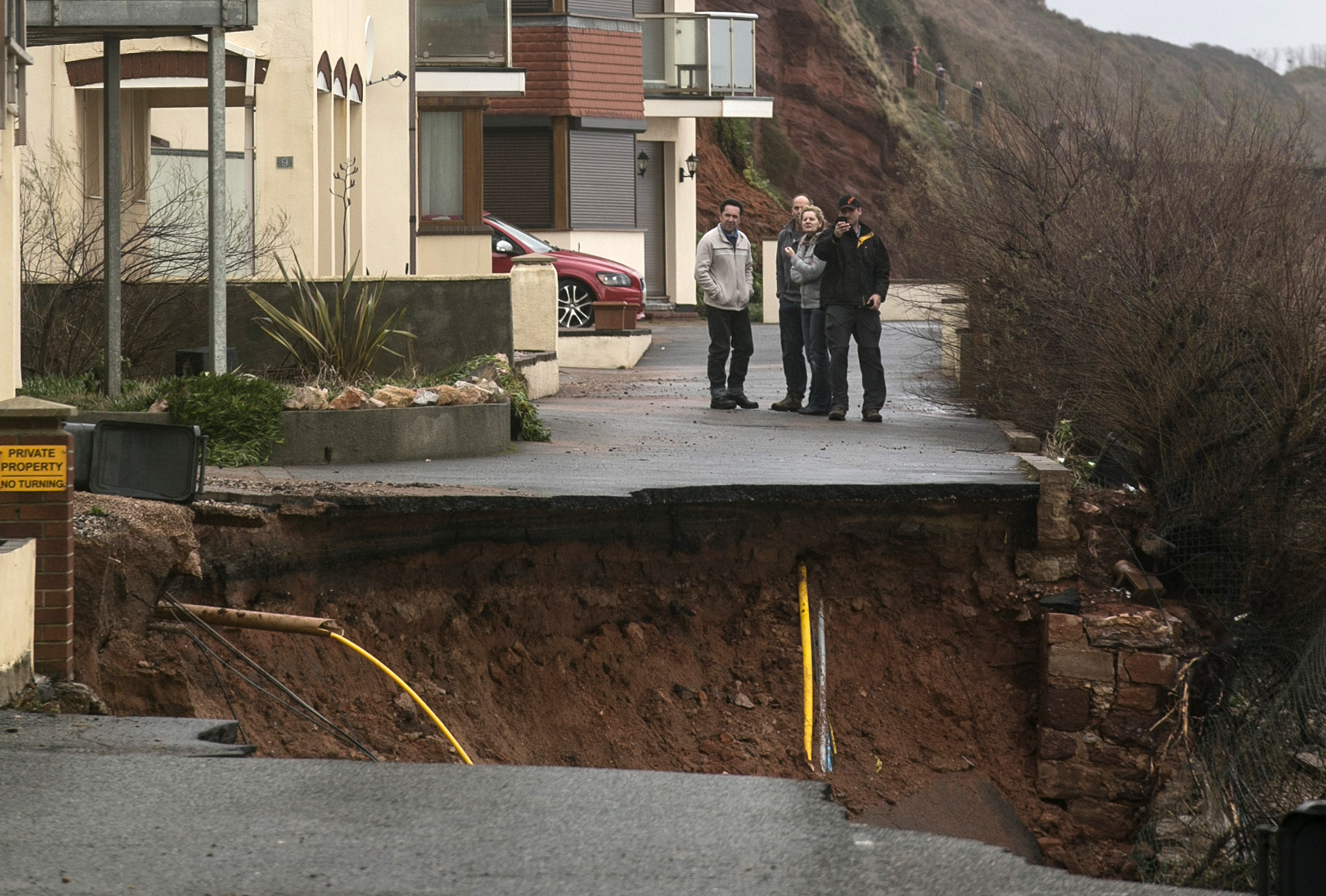 DAWLISH, UNITED KINGDOM - FEBRUARY 05:Residents look at a road that has been partly washed away by the sea at Dawlish on February 5, 2014 in Devon, England. With high tides combined with gale