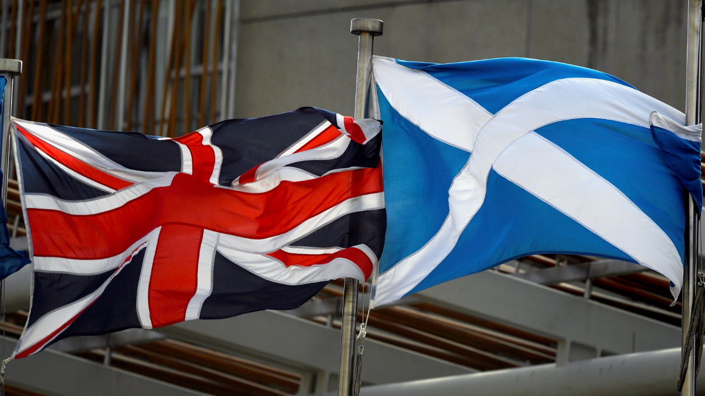 A Scottish Saltire and Union Jack flags flutter outside the Scottish Parliament