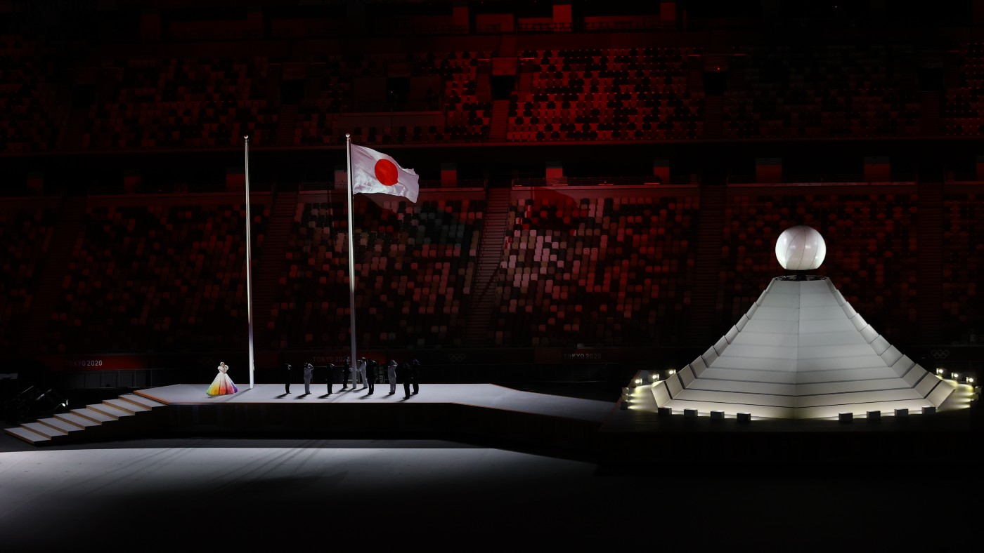A performer sings in front of the Japanese flag during the opening ceremony 