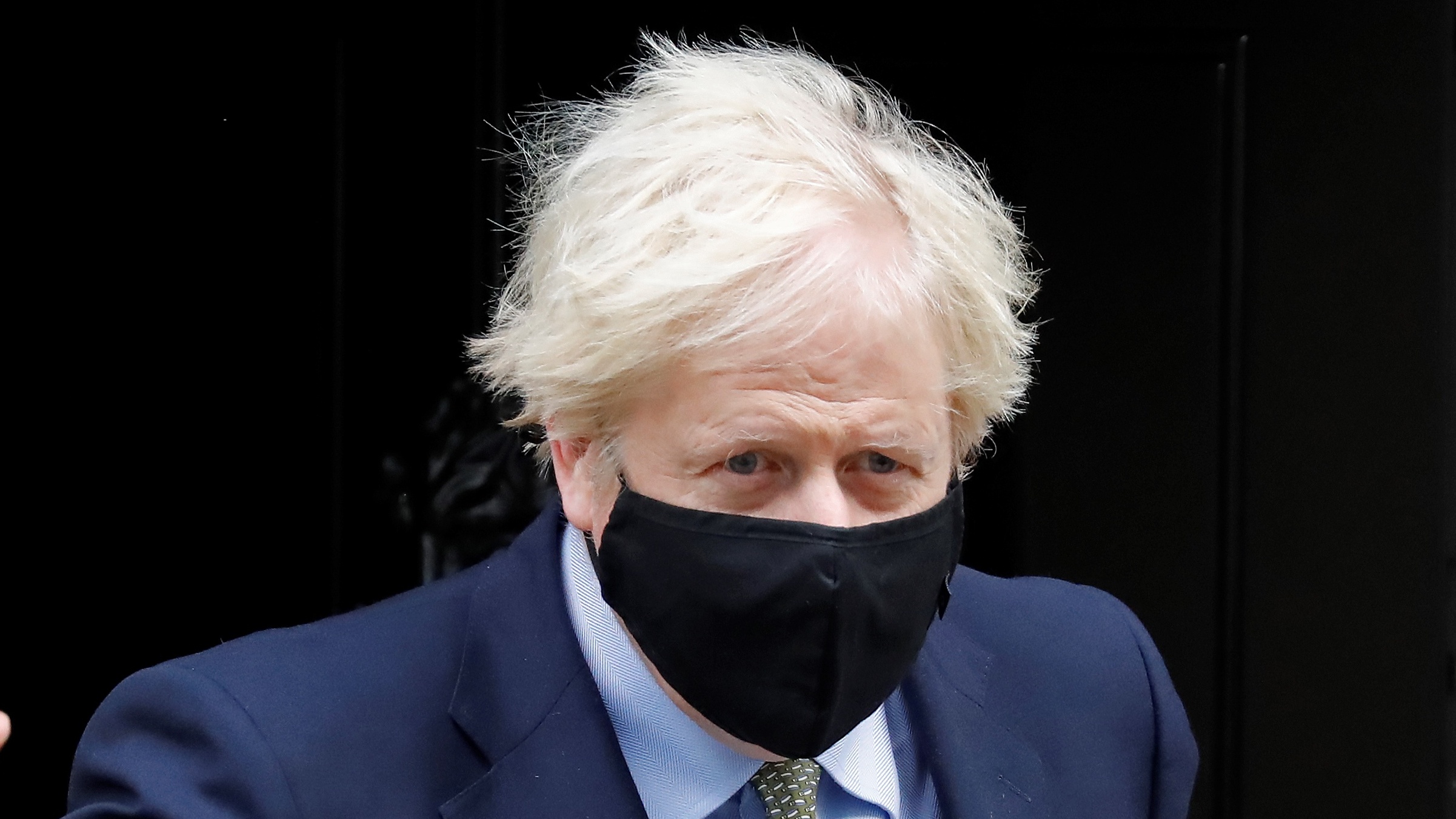 Boris Johnson leaves Downing Street wearing a black face mask.