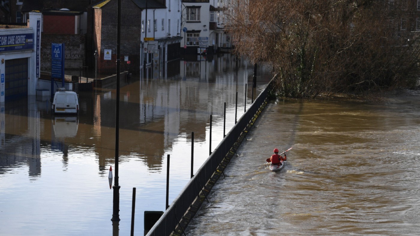A canoeist paddles along floodwaters