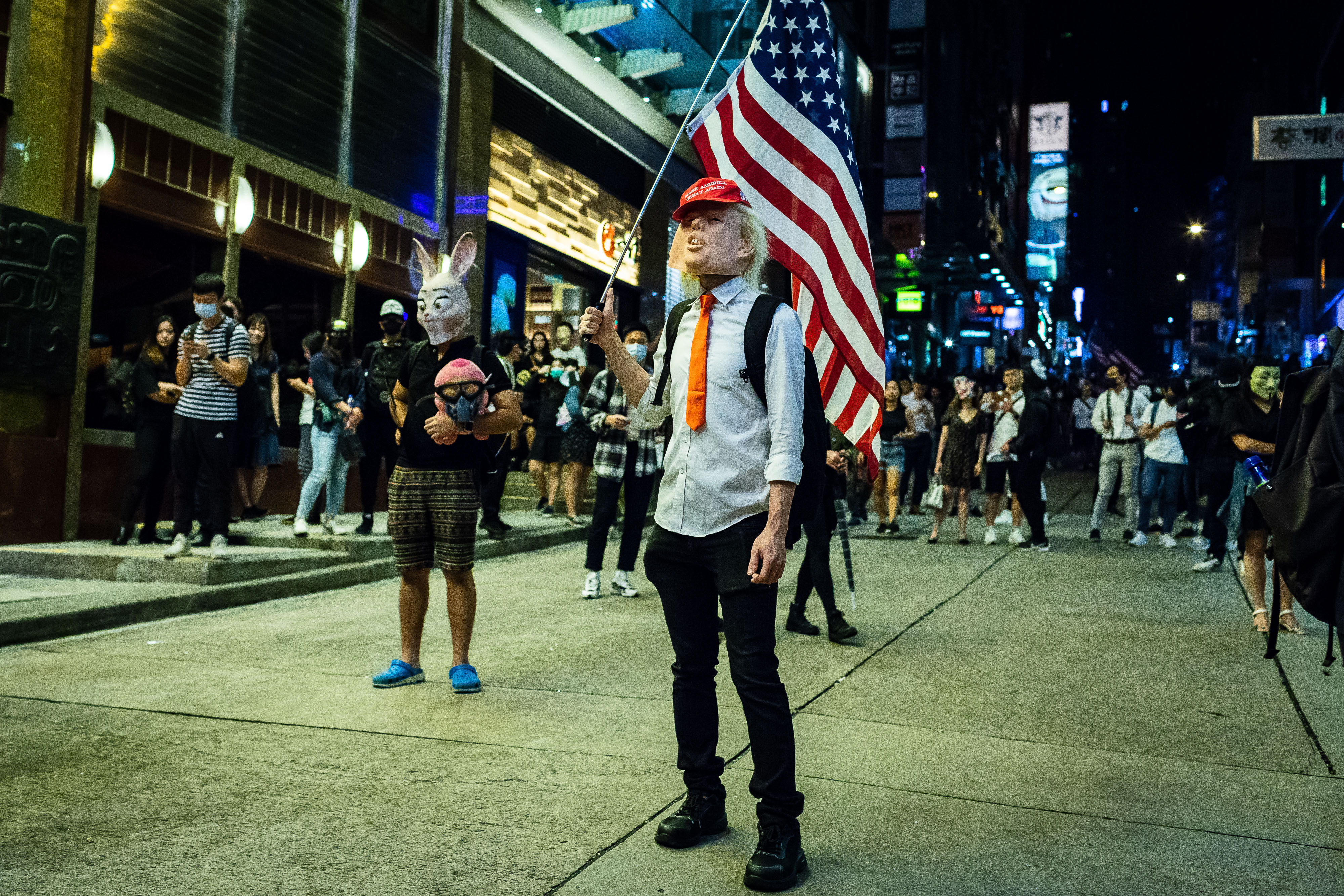 A demonstrator wears a Donald Trump mask while holding a U.S. flag in the Lan Kwai Fong area of Hong Kong, China, on Thursday, Oct. 31, 2019. Efforts by Hong Kongs authorities to quell the pr